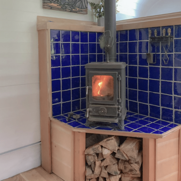 skoolie wood stove area with under wood storage