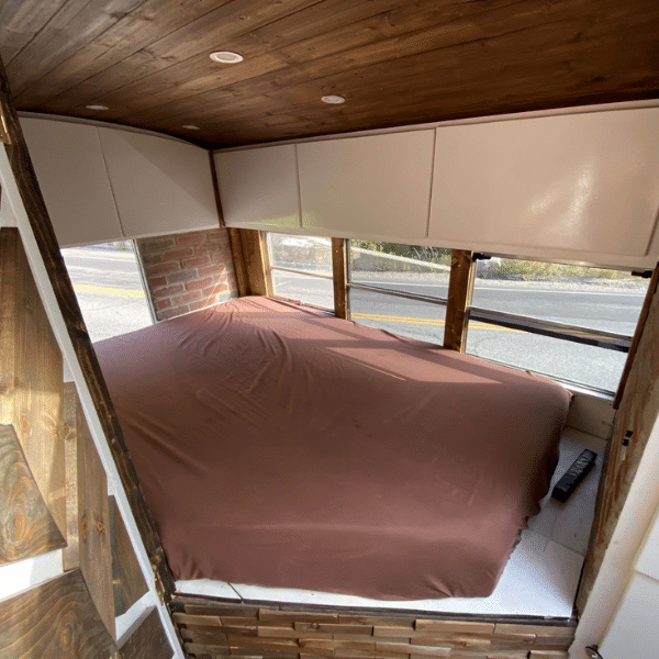 skoolie bedroom with overhead storage and custom mattress